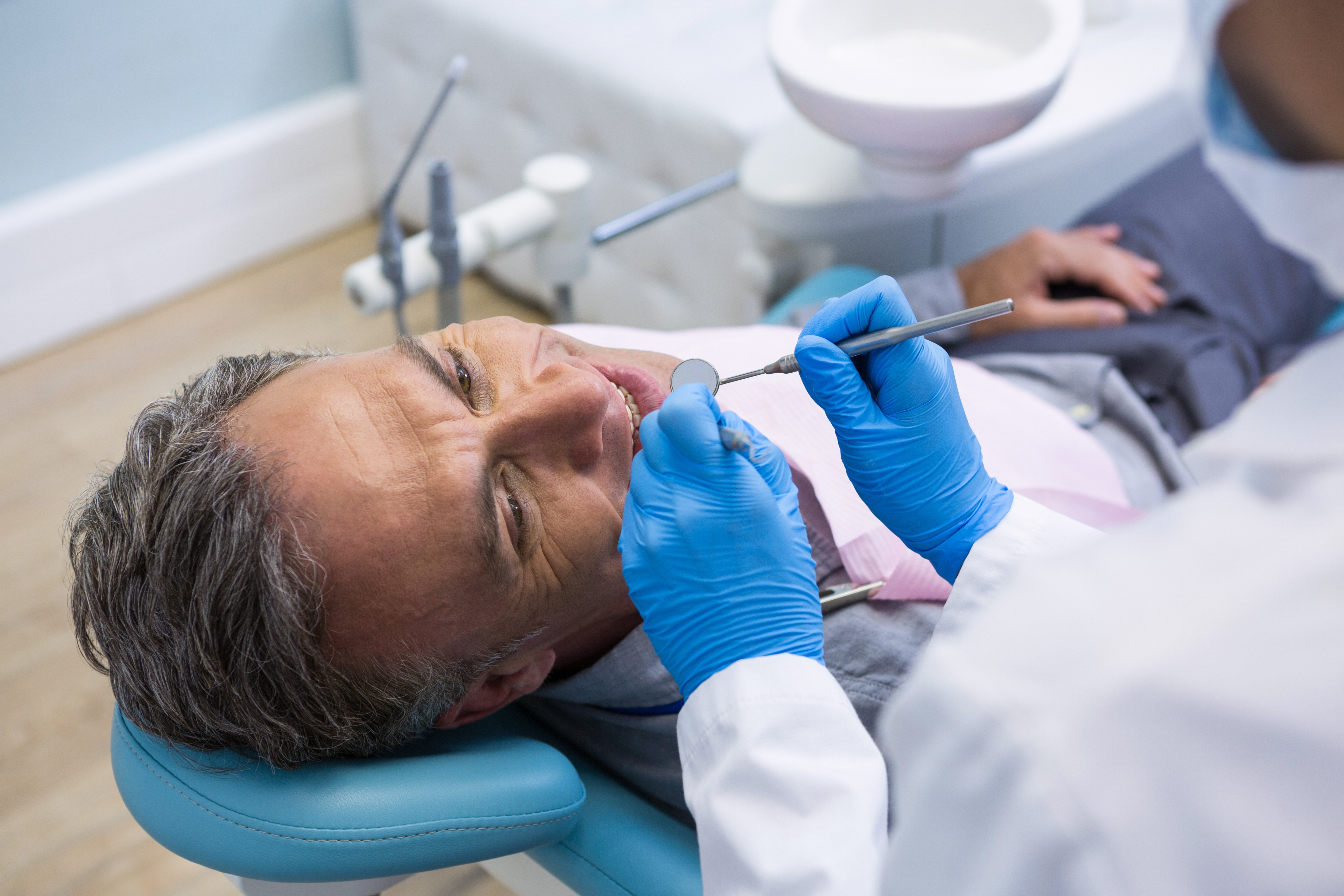 Can Gum Disease Be Cured - High angle view of dentist examining senior man