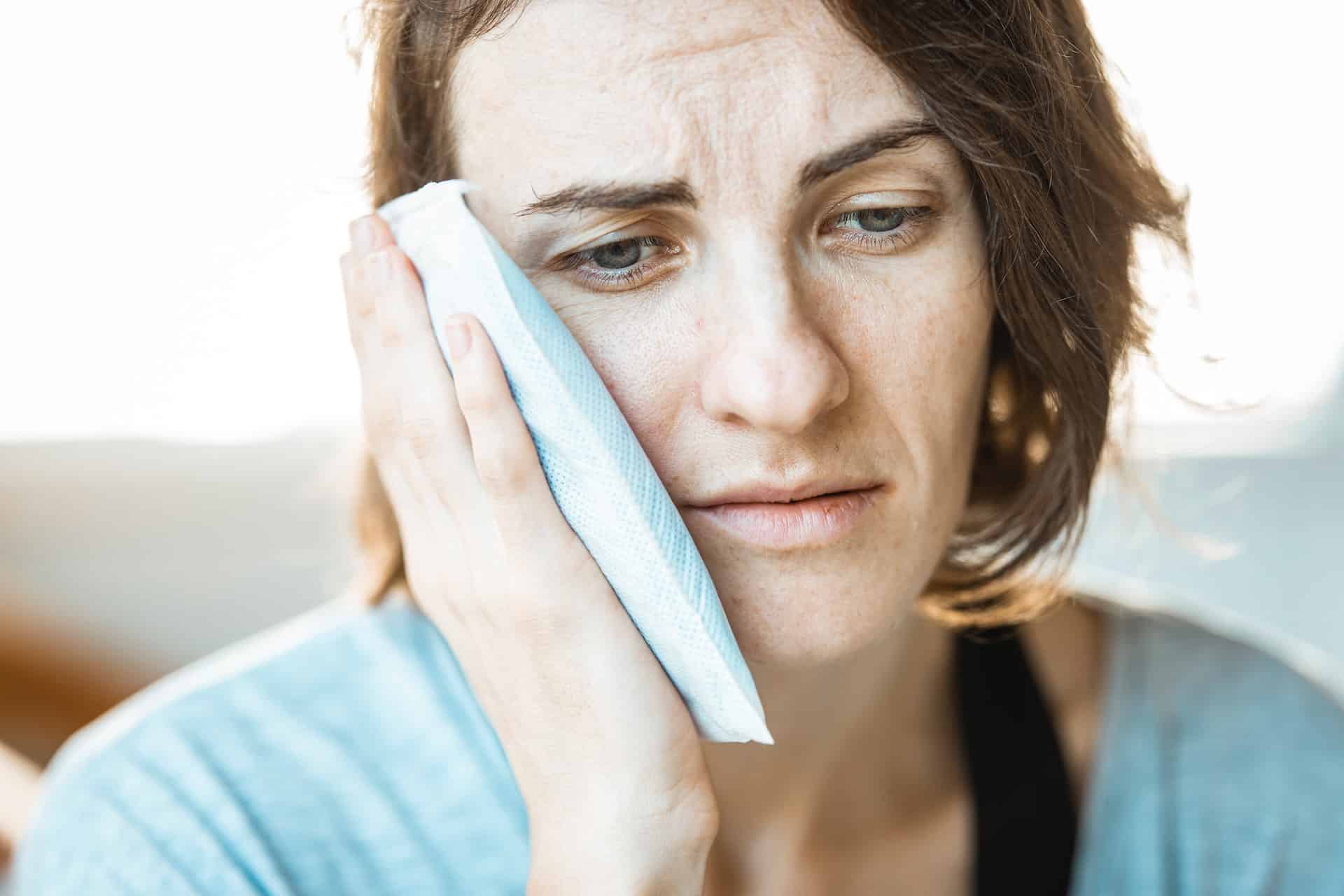 natural remedies for toothache - woman holding ice pack to face