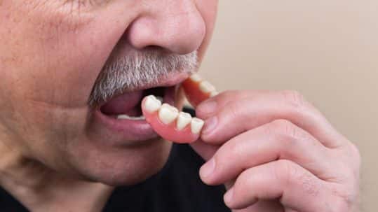 close up of older man putting partials in mouth