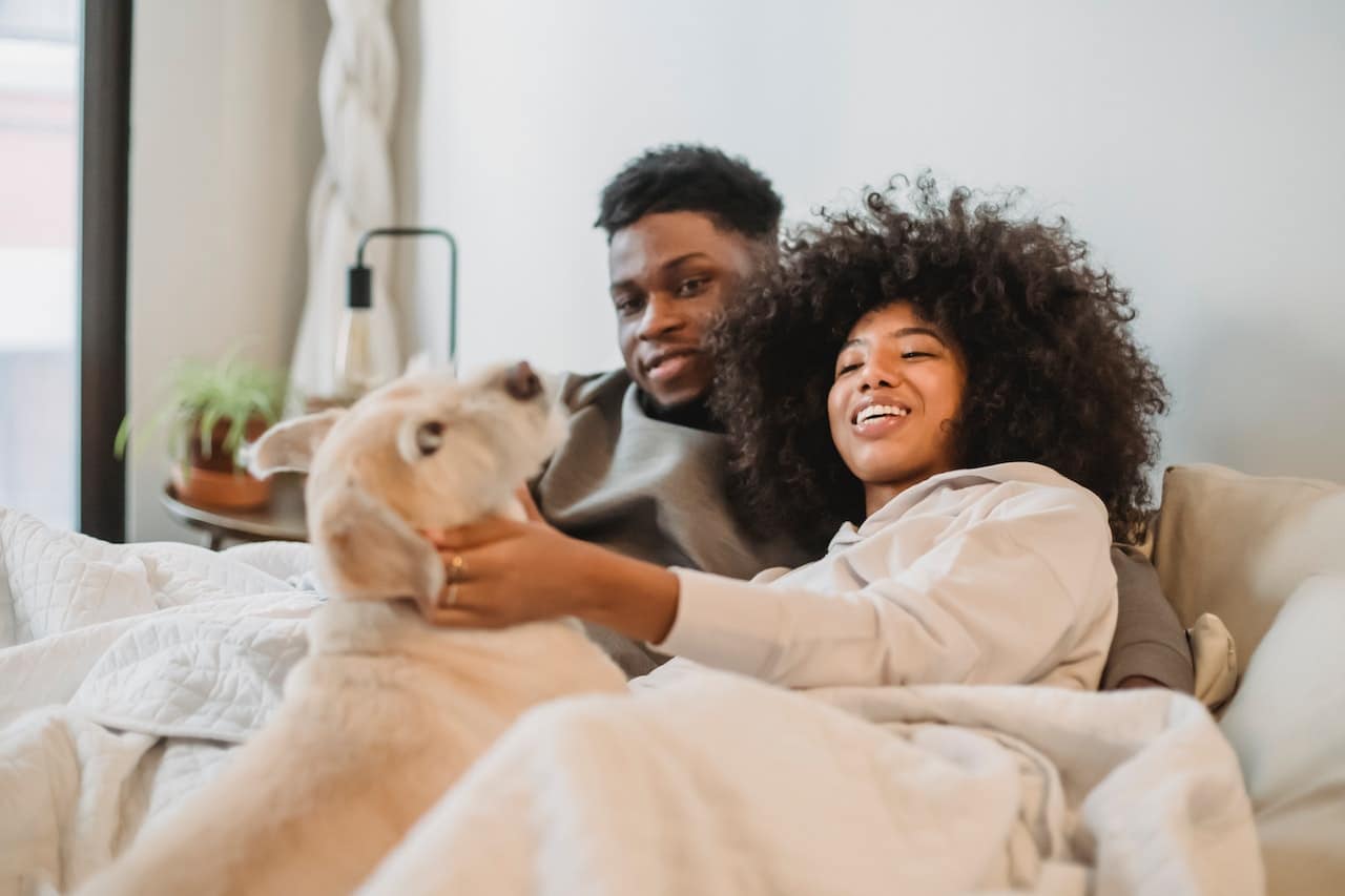 couple smiling relaxing on couch with dog