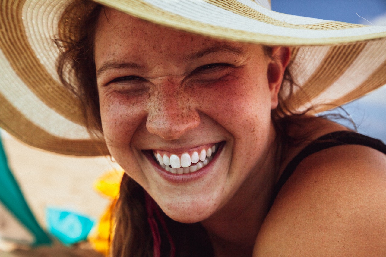 freckled woman wearing sun hat smiling