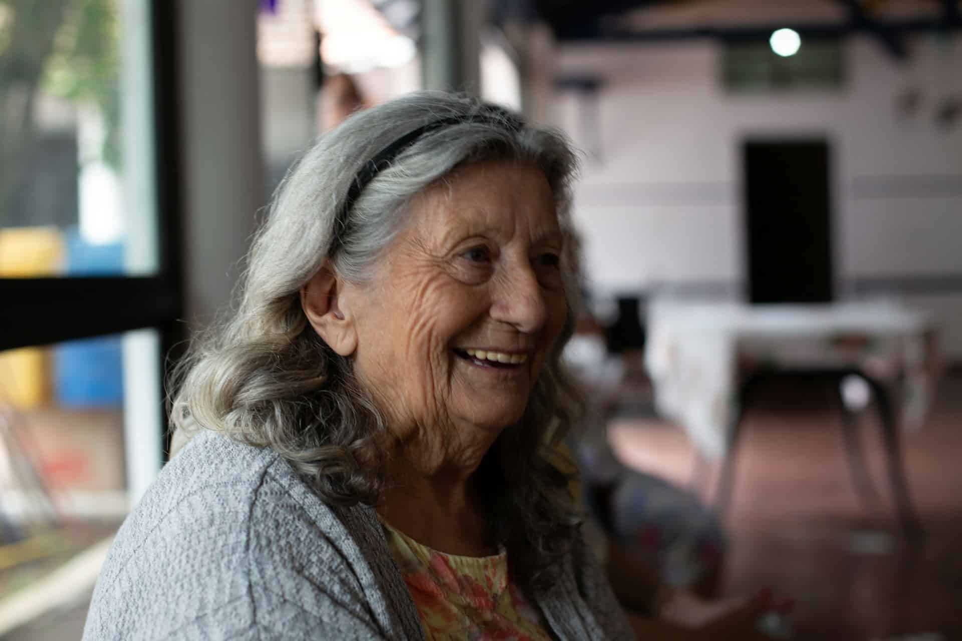 older woman in a gray cardigan smiling