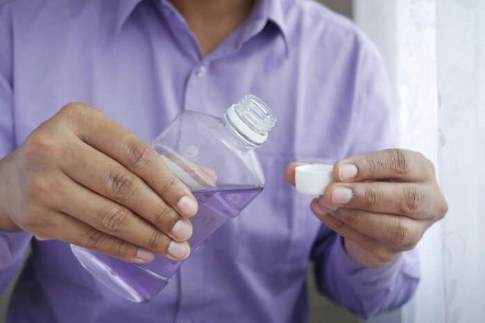 a person pouring purple mouthwash
