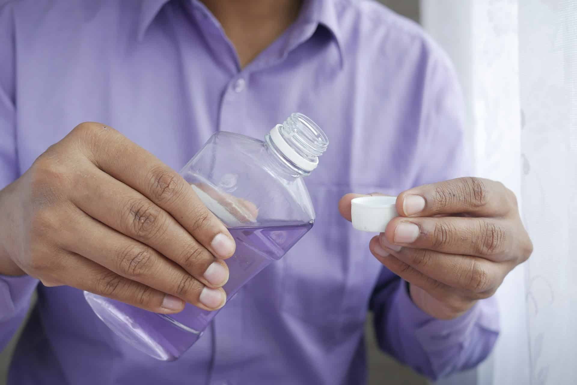 a person pouring purple mouthwash