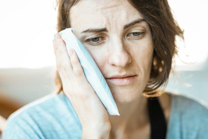 Woman with dental pain holding ice pack to face