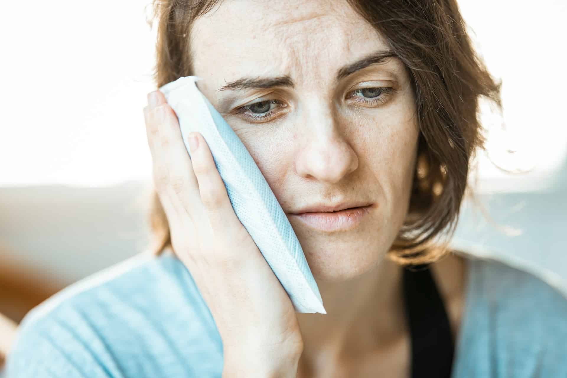 woman with ice pack on cheek